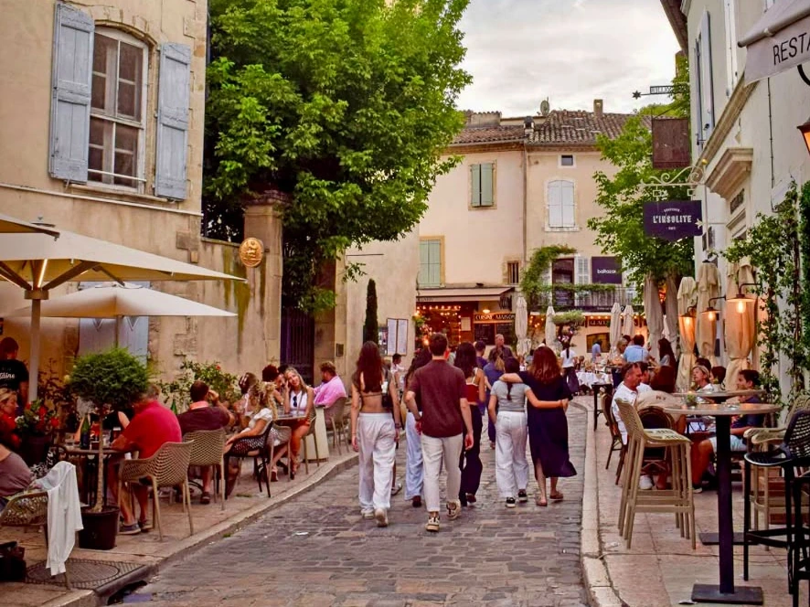 Rue animée du village de Lourmarin, terrasses de cafés et façades provençales