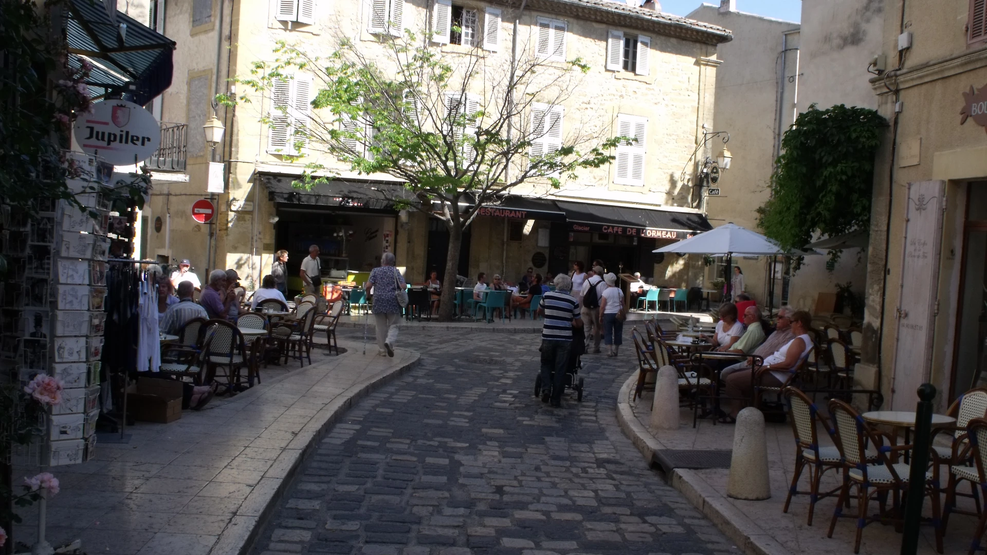 Rue pavée de Lourmarin bordée de cafés et de terrasses, au cœur du village