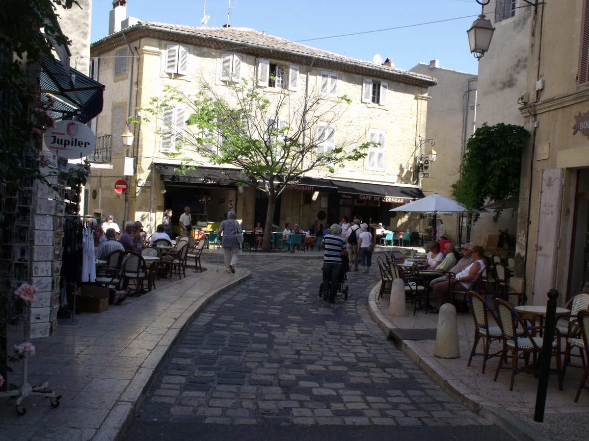 Rue pavée de Lourmarin bordée de cafés et de terrasses, au cœur du village