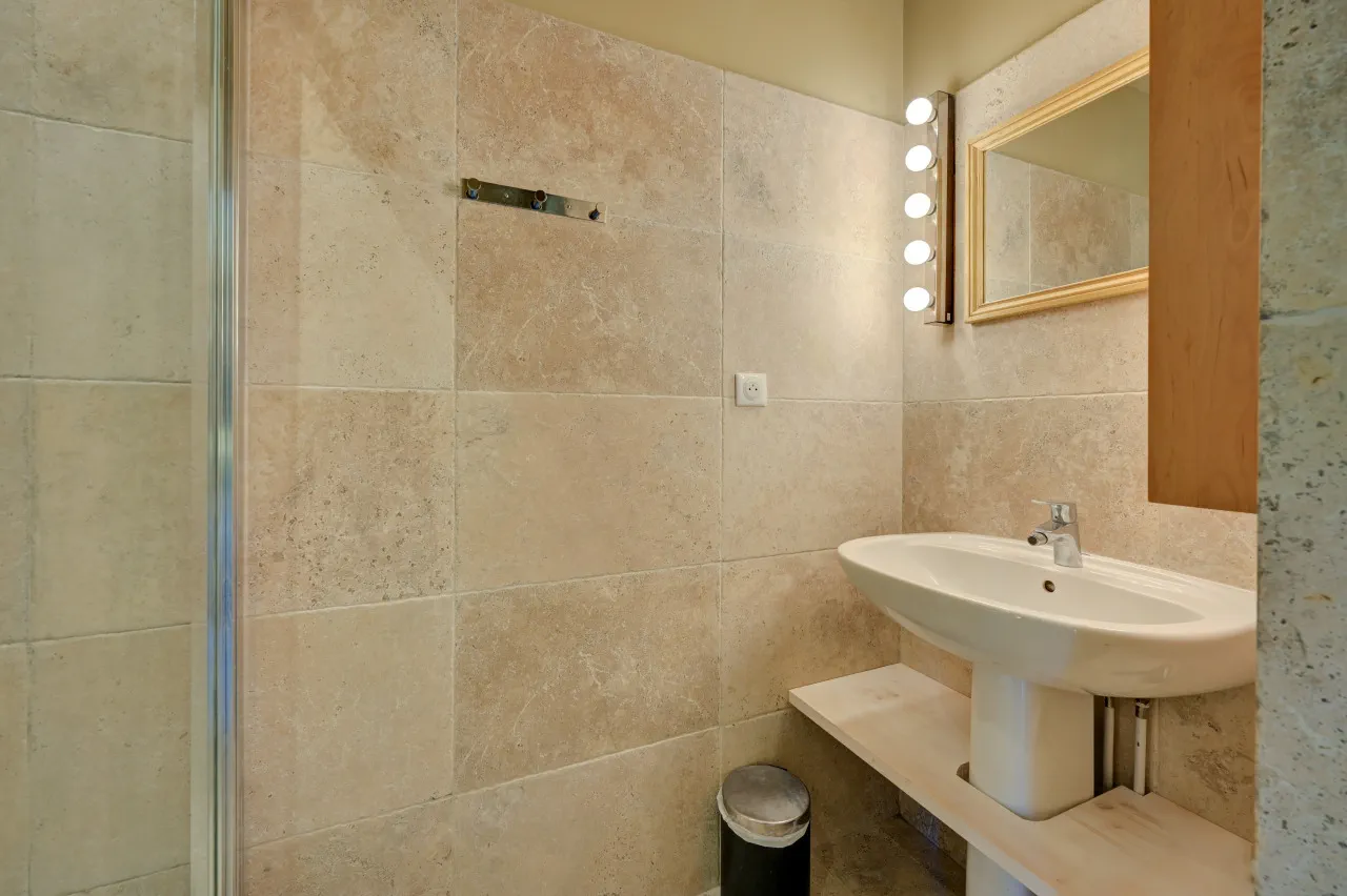 Douche et lavabo de la salle de bains habillée de pierre claire, chambre Capri, Lourmarin