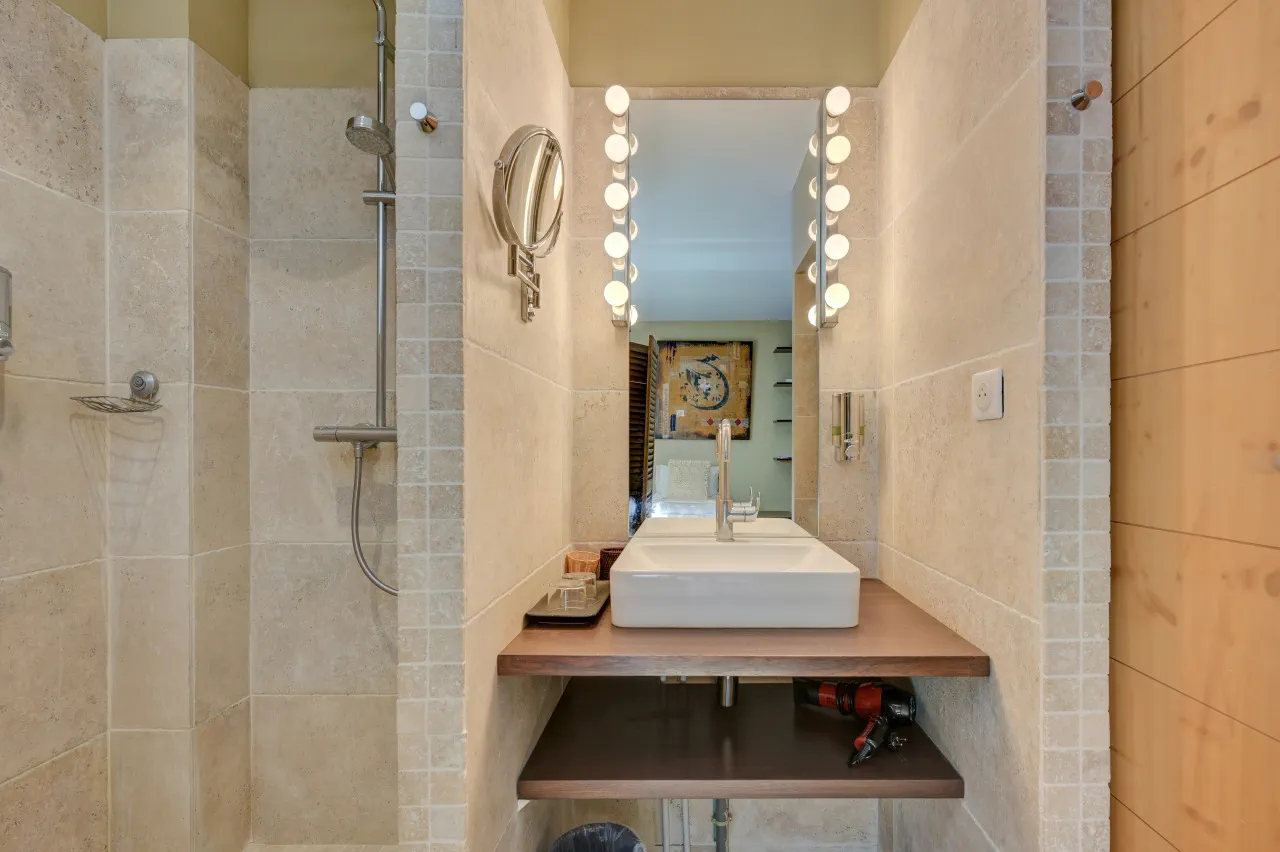 Vasque posée sur un plan en bois, miroir à ampoules et douche à l'italienne, salle de bains de la chambre Capri, Lourmarin