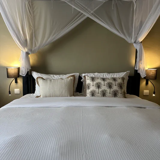 Chambre Bali, lit à baldaquin en bois sous moustiquaire déployée, hôtel O Mamma Mia à Lourmarin
