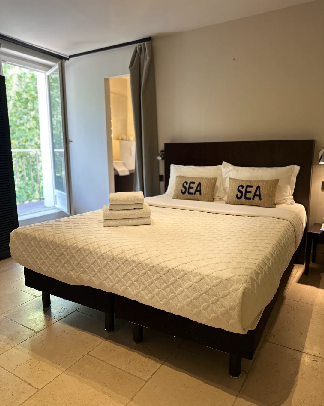 Lit double et fenêtre ouverte sur la végétation, chambre Venezia, hôtel O Mamma Mia, Lourmarin