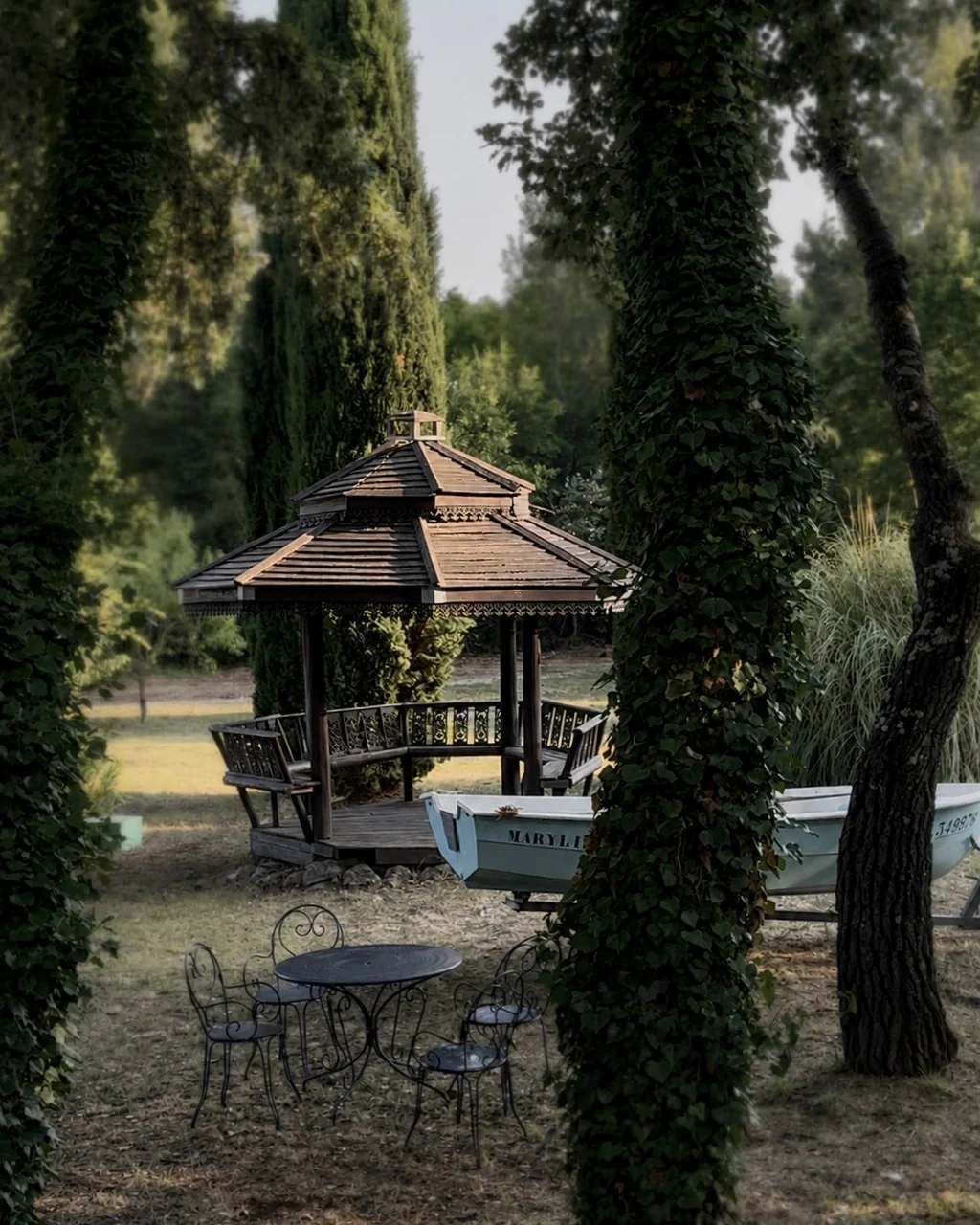 Kiosque en bois et table en fer forgé sous les cyprès du parc, hôtel O Mamma Mia à Lourmarin