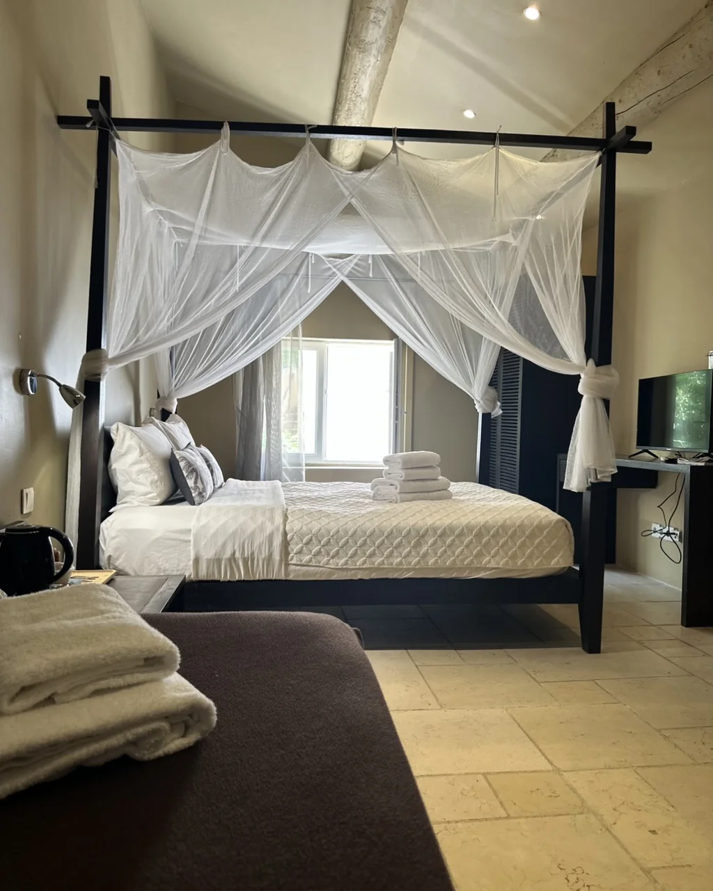 Chambre avec lit à baldaquin, moustiquaire et sol en pierre, hôtel O Mamma Mia à Lourmarin