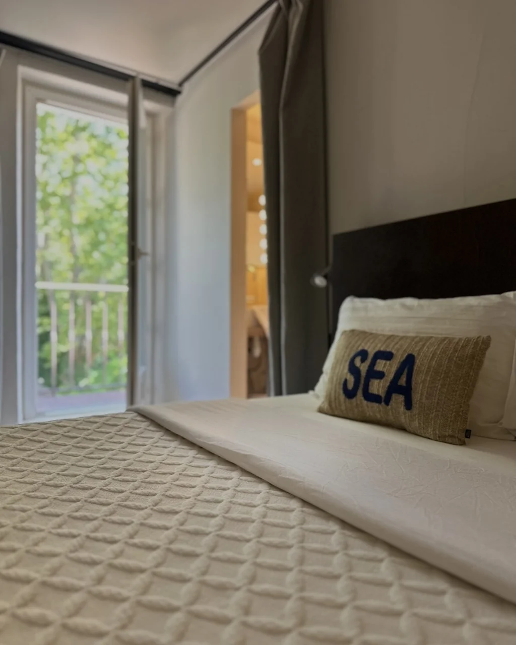 Lit ouvert sur la porte-fenêtre du balcon et la salle de bains, hôtel O Mamma Mia à Lourmarin