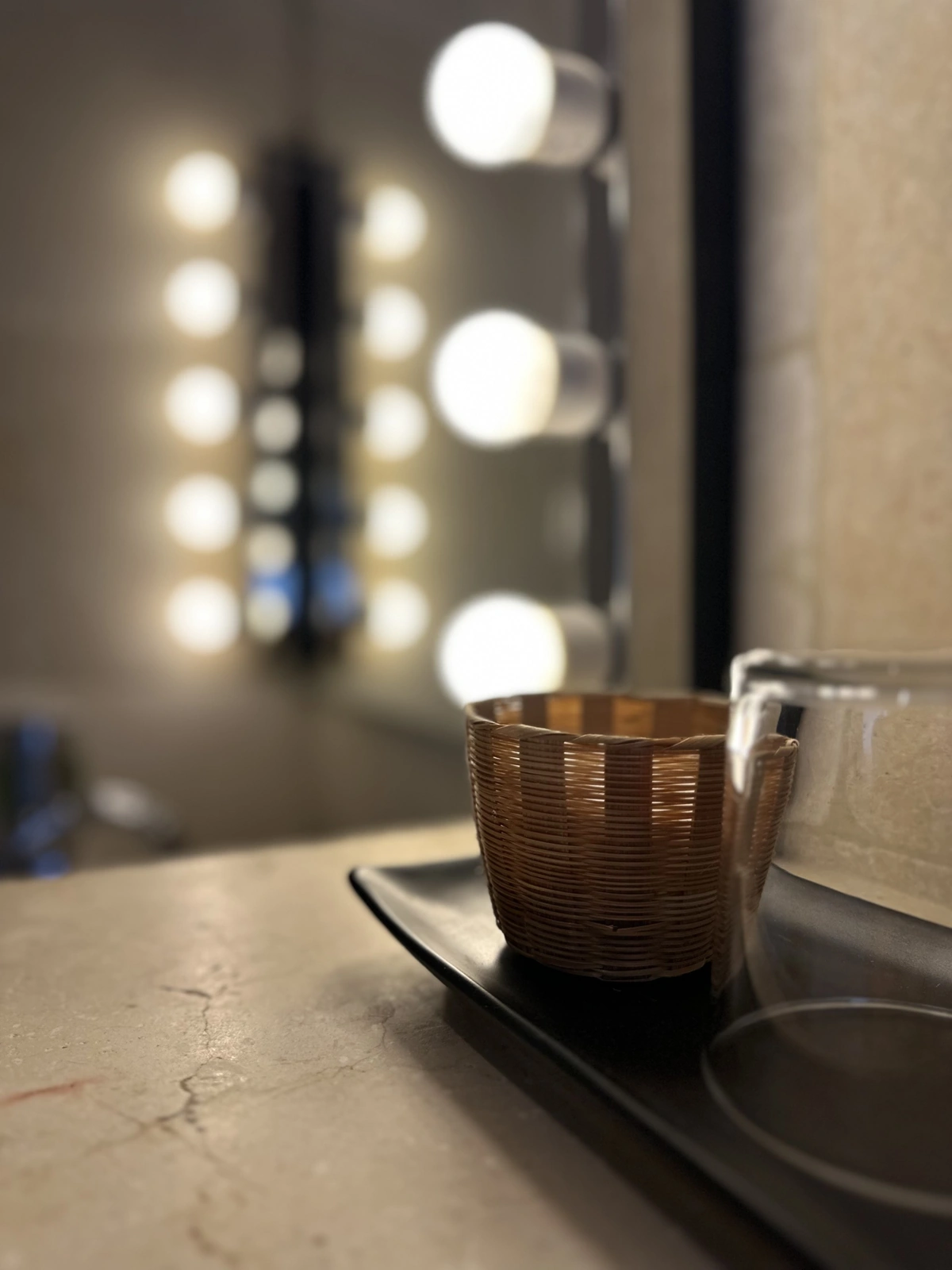 Détail d'une salle de bains : miroir à ampoules et verre en rotin sur la tablette, hôtel O Mamma Mia à Lourmarin