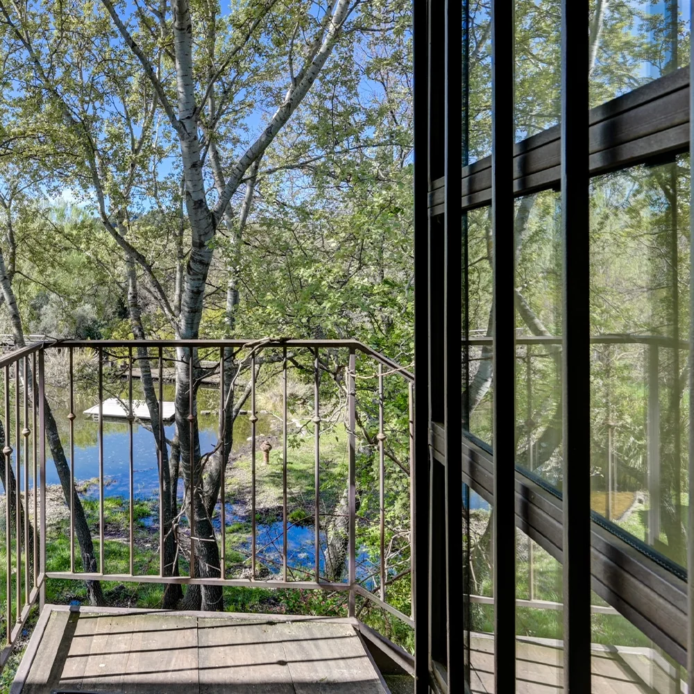 Balcon en bois surplombant le plan d'eau naturel arboré, hôtel O Mamma Mia à Lourmarin