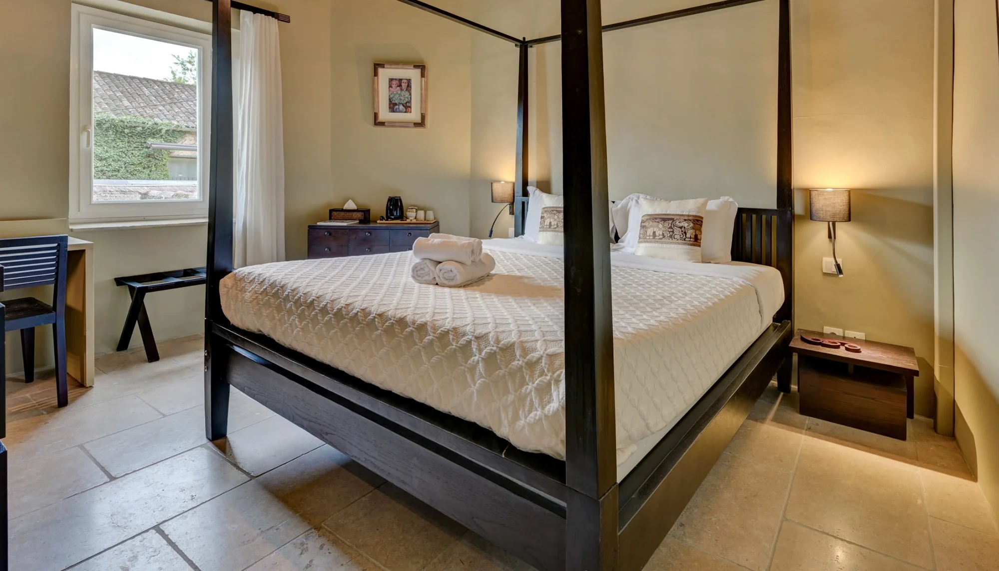 Lit à baldaquin, bureau et fenêtre donnant sur les toits, hôtel O Mamma Mia à Lourmarin
