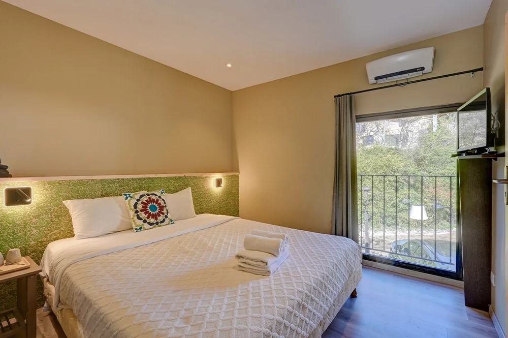 Lit double devant une tête de lit à motifs verts, hôtel O Mamma Mia à Lourmarin