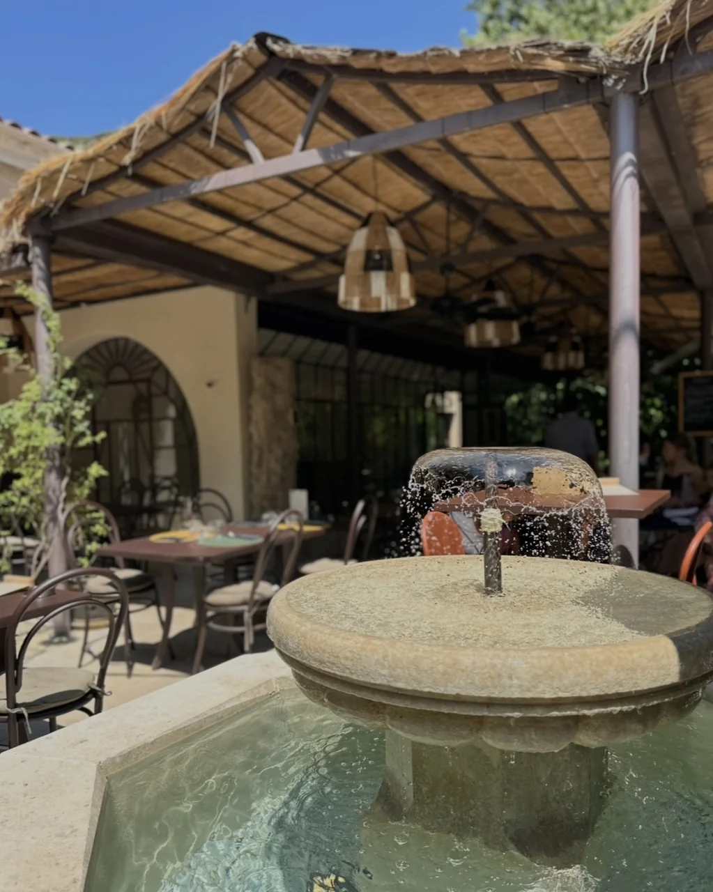 Fontaine et pergola en roseaux au-dessus des tables, restaurant O Mamma Mia à Lourmarin