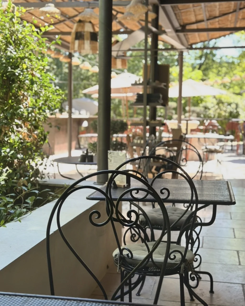 Chaises en fer forgé et parasols blancs sur la terrasse ombragée, restaurant O Mamma Mia à Lourmarin