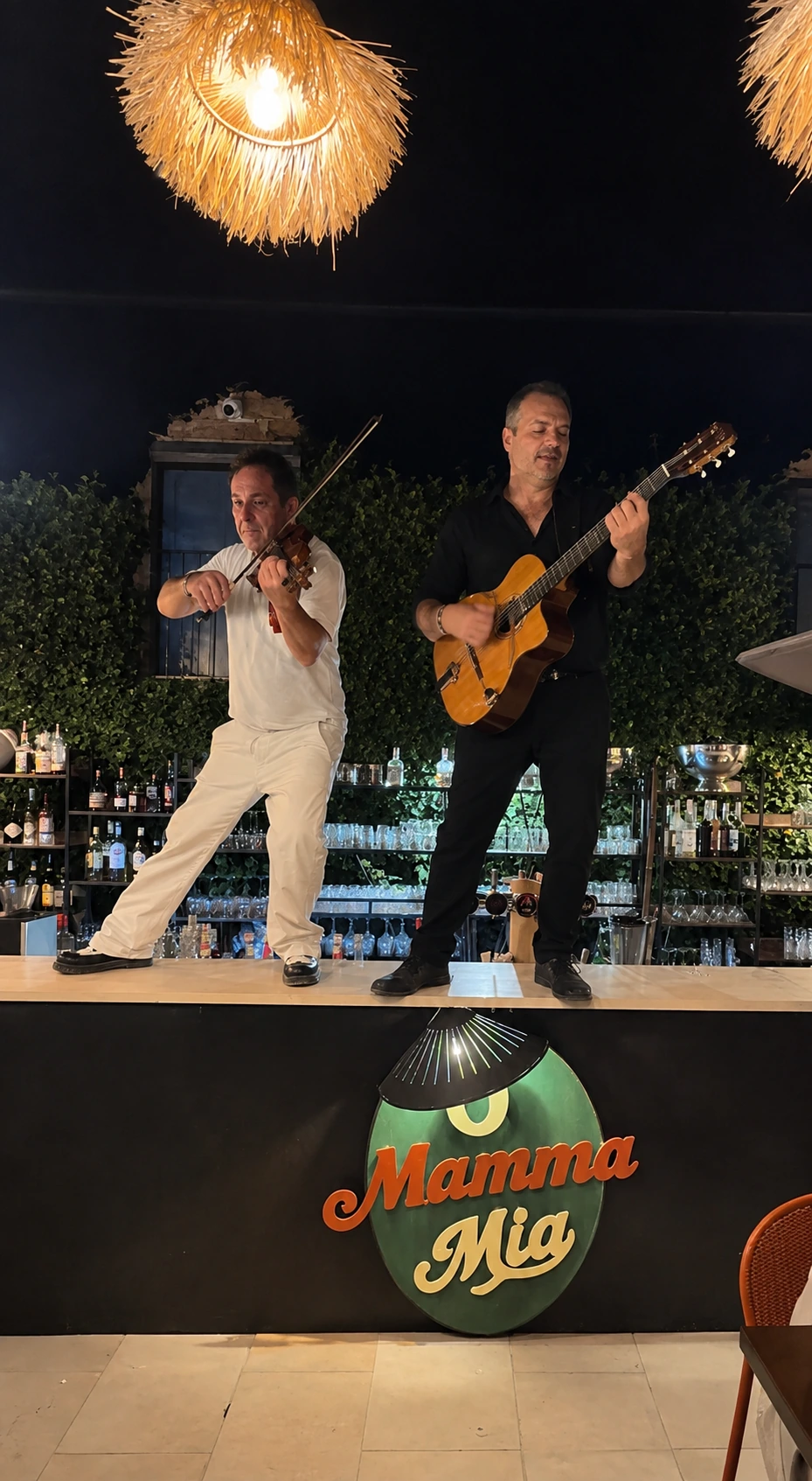 Violoniste et guitariste sous les suspensions en paille, soirée O Mamma Live à Lourmarin